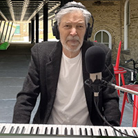 screen shot from music video showing Jonathan Ochshorn sitting at keyboard in front of the Milstein Halll arcade